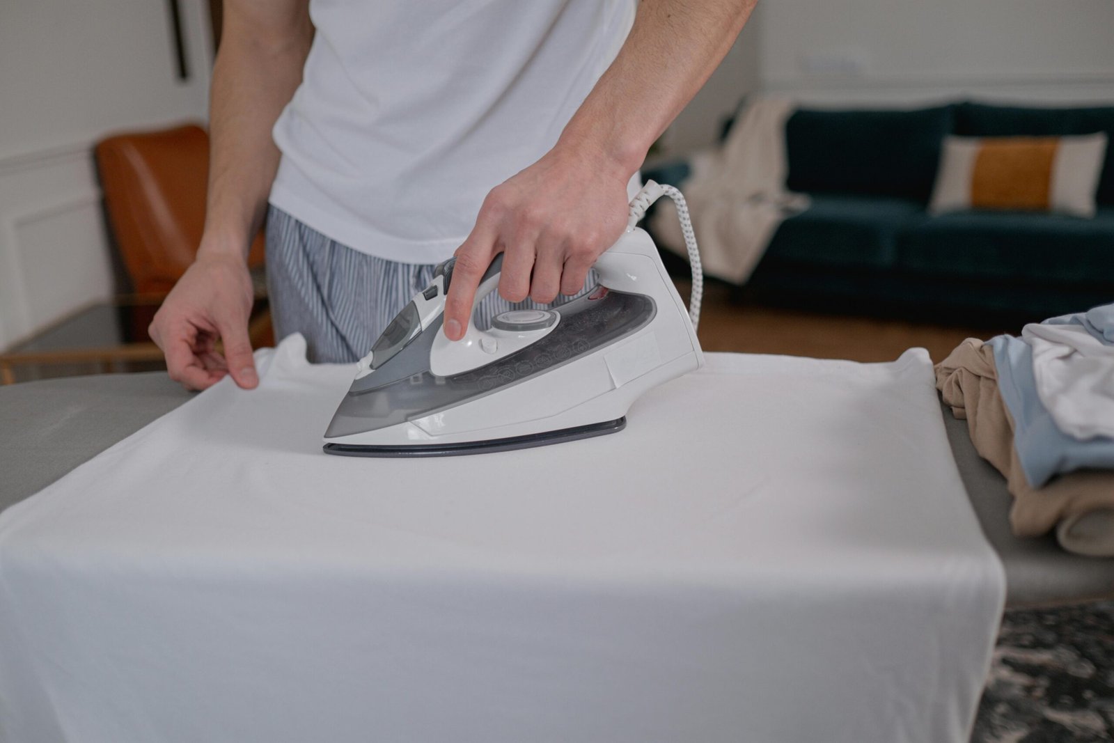 A man irons clothes on an ironing board in a stylish apartment setting.